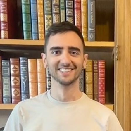 Corey Carvalho in front of library bookshelves